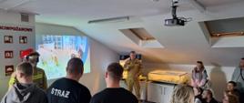 Strażak przy pomocy mobilnego symulatora zagrożeń pożarowych omawia zagrożenia występujące w naszych domach