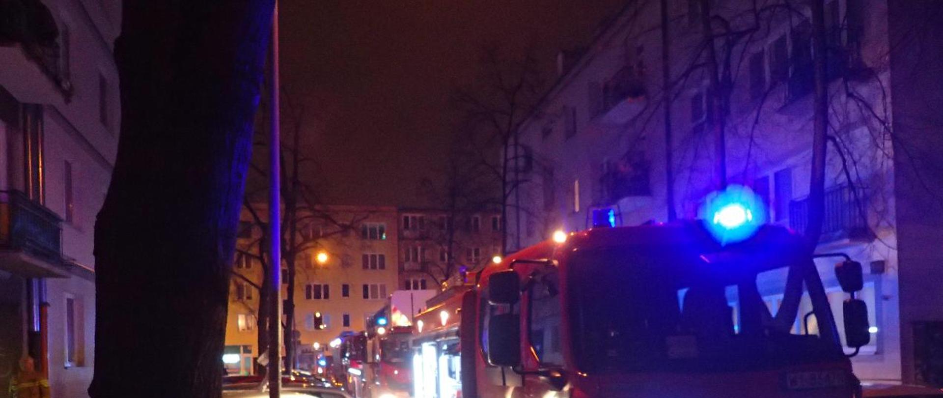 na zdjęciu widać trzy samochody straży pożarnej stojące na ulicy z włączonymi sygnałami świetlnymi