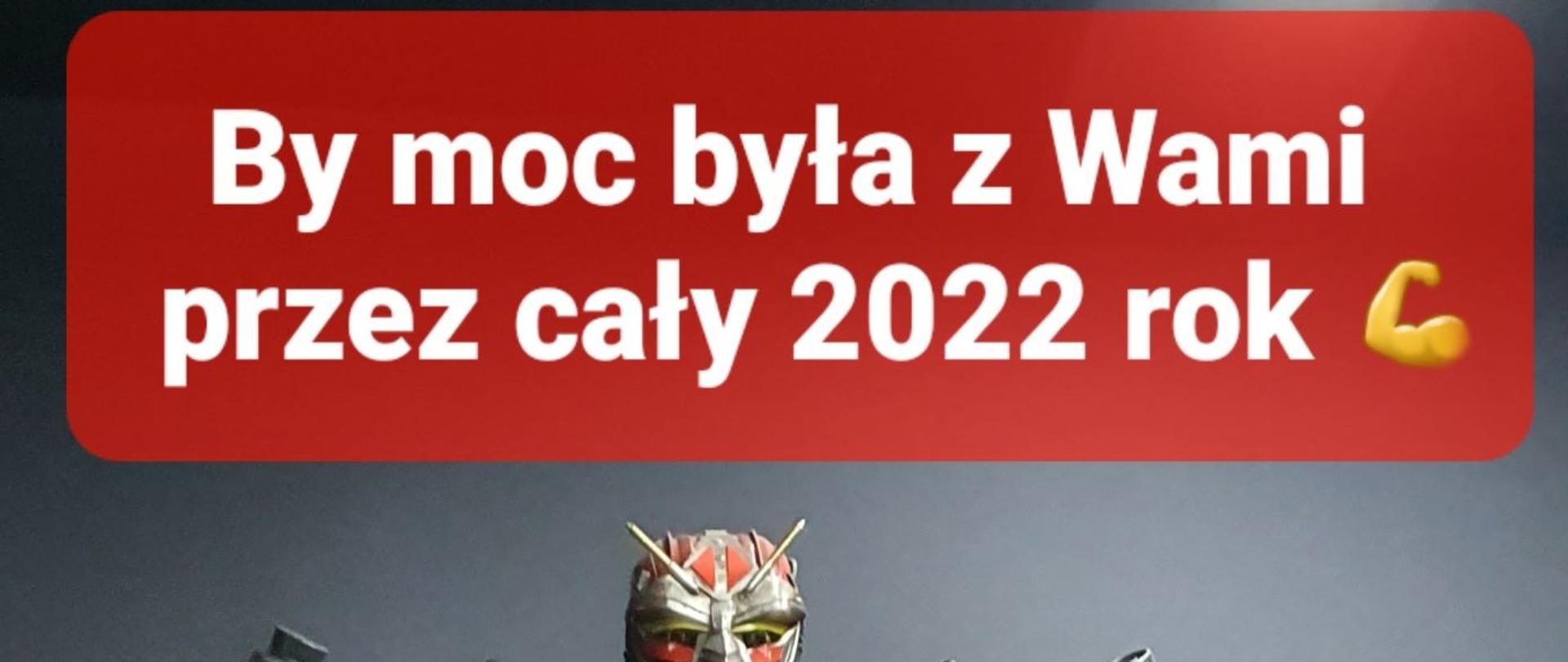 Zdjęcie przedstawia czerwono-srebrnego robota strażackiego zbudowanego z części samochodowych. W górnej części biały napis "By moc była z Wami przez cały 2022 rok" na czerwonym tle. W części części biały napis "Funkcjonariusze i pracownicy KM PSP w Grudziądzu" na czerwonym tle.