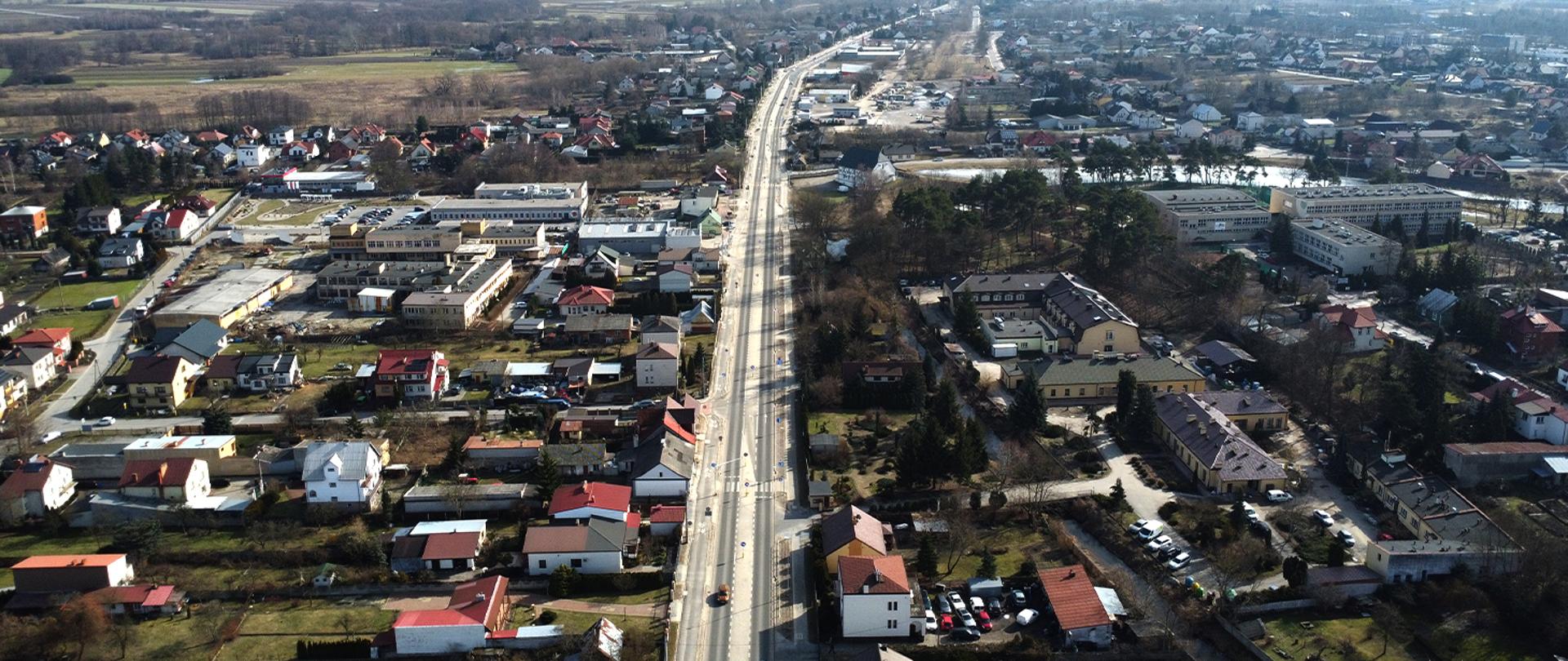 Widok z góry na drogę krajową przebiegającą przez Kozienice, z zabudową miejską po obu stronach.