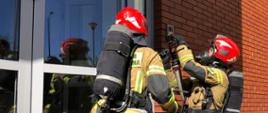 Ćwiczenia pożary wewnętrzne - JRG Grójec rota strażaków w aparatach ODO przed wejściem do budynku 