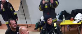 Zdjęcie przedstawia trzech strażaków i pozoranta leżącego na noszach