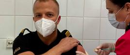 Widoczny funkcjonariusza psp i osoba dokonująca szczepienia przeciw COVID-19