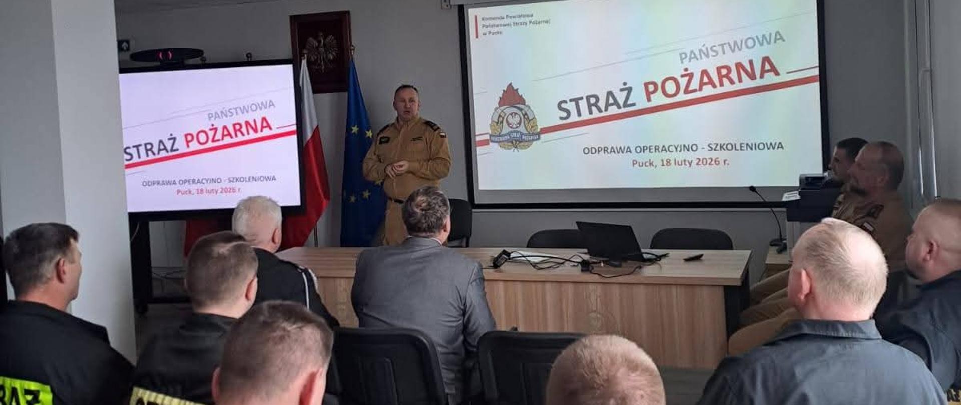 Komendant Powiatowy PSP w Pucku bryg. Wojciech Wanat otwiera odprawę Operacyjno-Szkoleniową. Komendant ubrany jest w strój służbowy w kolorze piaskowym. 