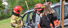 Strażak prowadzi pokaz uwolnienia osoby poszkodowanej z pojazdu przy użyciu narzędzi hydraulicznych