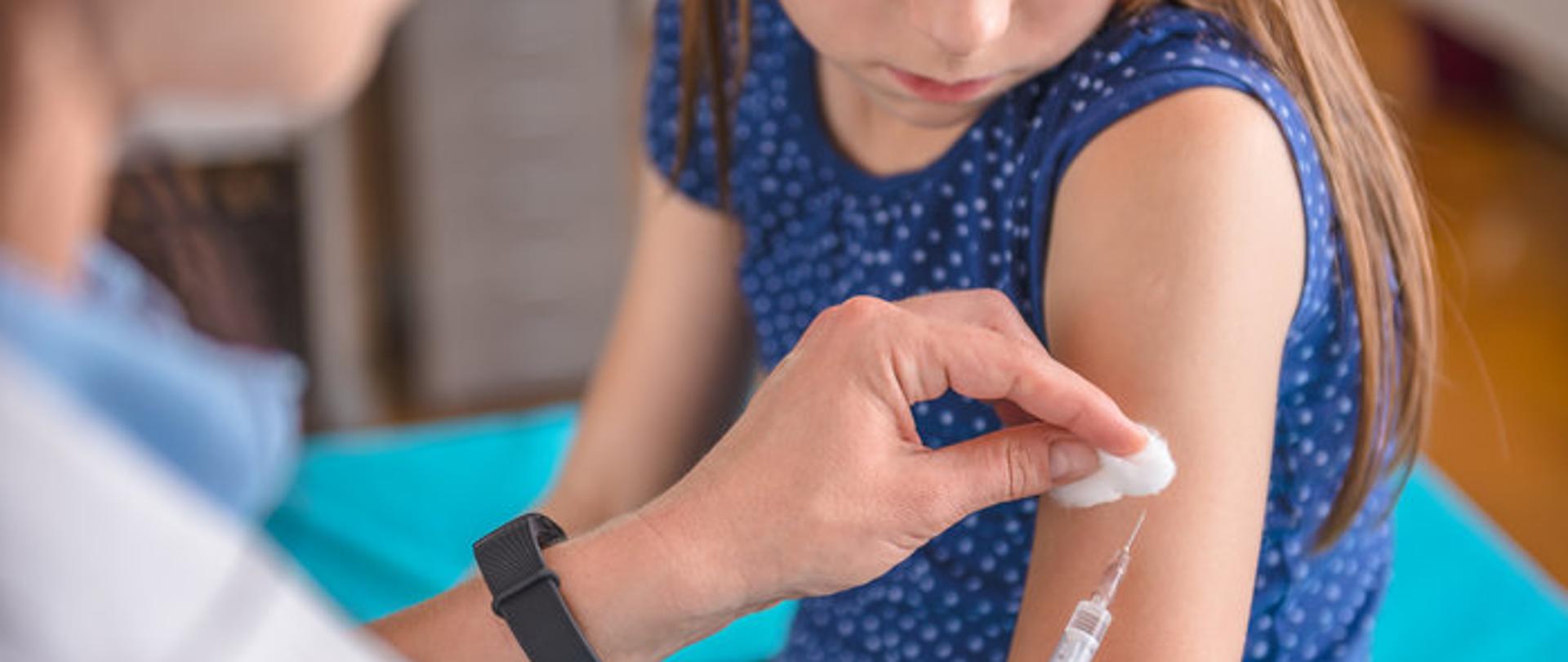 Pracownik medyczny szczepi małą dziewczynkę