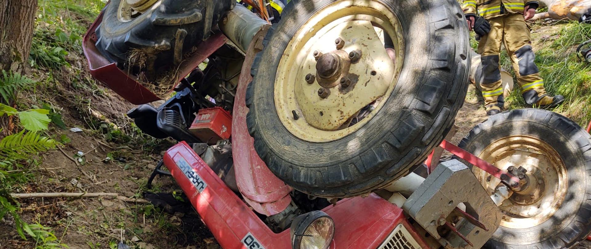 Ciągnik rolniczy leżący do góry kołami