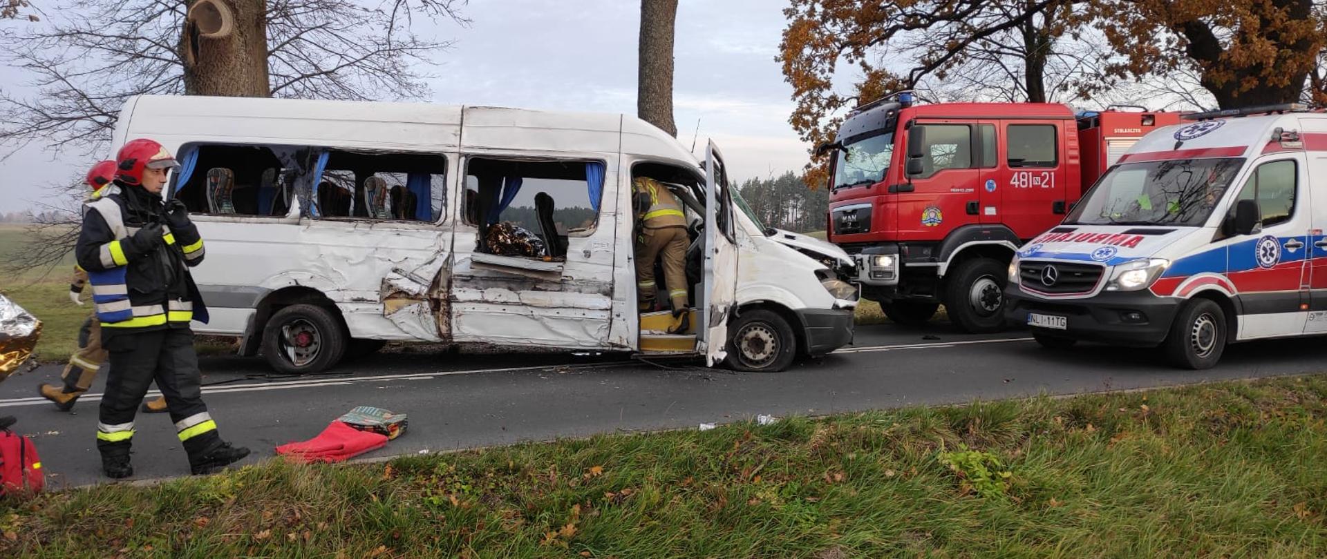 Zdjęcie przestawia uszkodzonego busa wraz z pojazdami PSP oraz karetką pogotowia. Na pierwszym planie Kierujący Działaniami Ratowniczymi.
