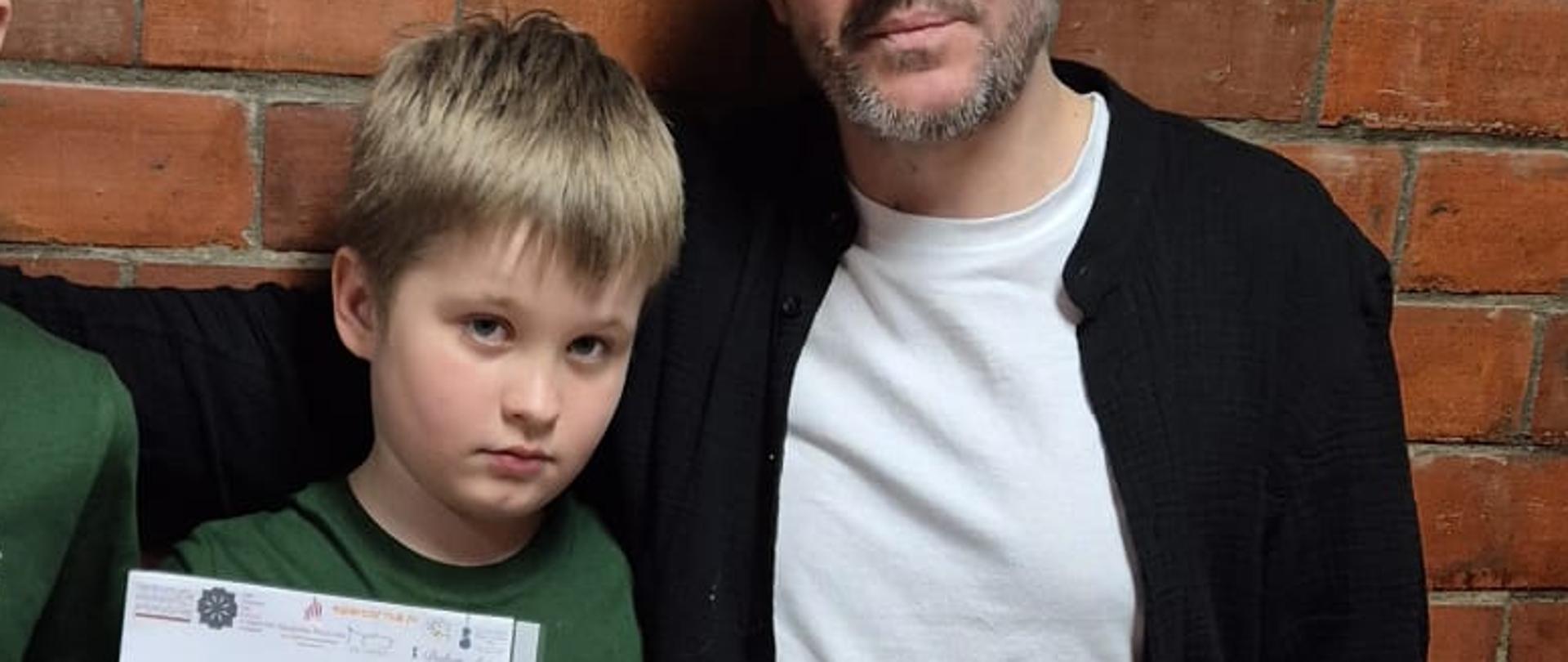 Nauczyciel klasy waltorni pan Tomasz Wójtowicz z uczniami Maciusiem w środku i Krzysiem z lewej strony. Uczniowie trzymają dyplomy z konkursu Młody Waltornista.