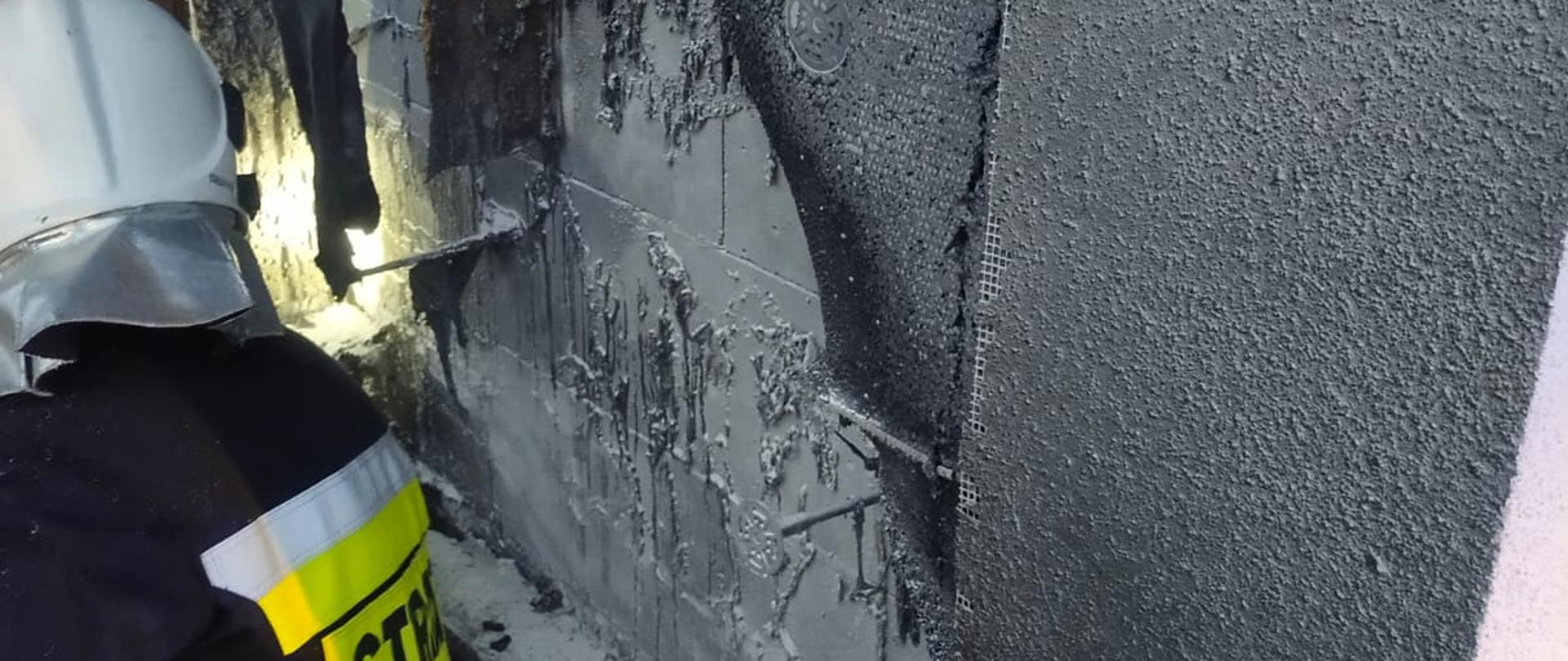 Strażak obok spalonej elewacji