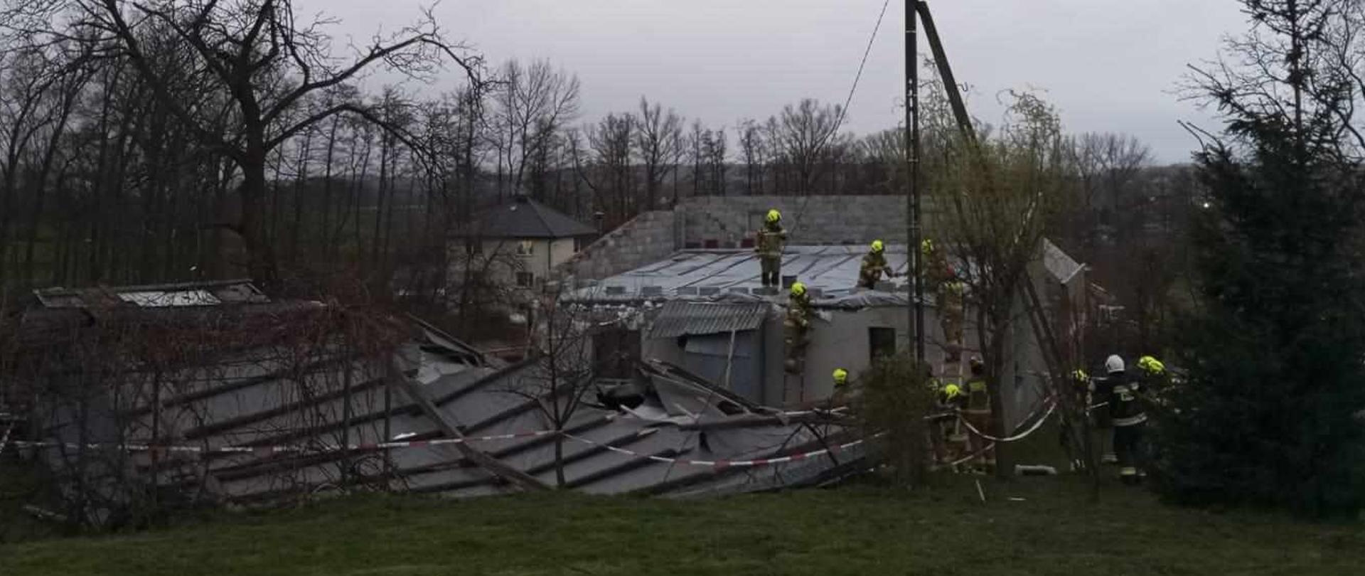 Zdjęcie przedstawia zerwany dach leżący obok parterowego budynku mieszkalnego. 