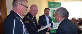 Na zdjęciu od lewej stoi prezes oddziału gminnego Związku Ochotniczych Straży Pożarnych, zastępca komendanta powiatowego PSP w Ostrzeszowie oraz wójt gminy Czajków, którzy wręczają decyzję o przyznaniu świadczenia.