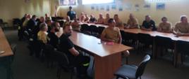Strażacy ochotnicy słuchają informacji przekazywanych na szkoleniu dotyczących zasad bezpiecznej jazdy pojazdami uprzywilejowanymi.