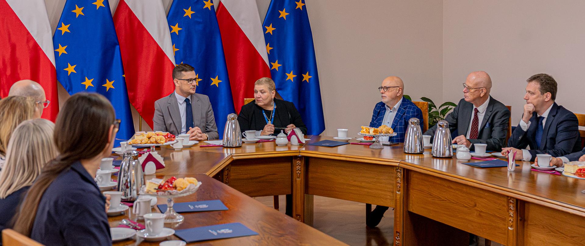 Wojewoda Michał Sztybel oraz Dyrektor Wydziału Zdrowia dr Dorota Doktór siedzą przy stole wraz z nowo powołanymi konsultantami wojewódzkimi w ochronie zdrowia. 