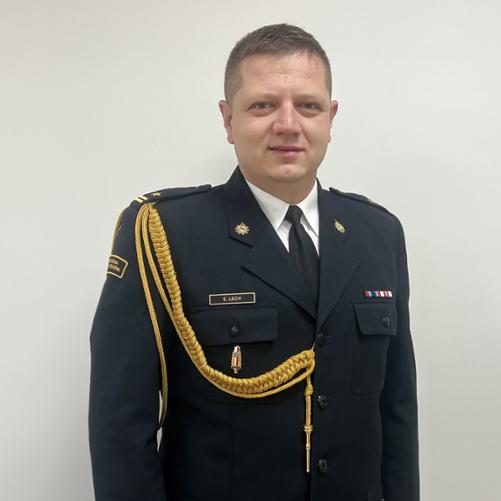 Zdjęcie przedstawia zastępcę komendanta powiatowego PSP w Tomaszowie Mazowieckim ubranego w mundur galowy ze złotym sznurem. 