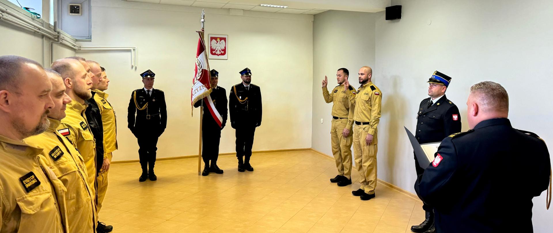 Ślubowanie strażaków. Na tle widoczni funkcjonariusze komendy wraz z sztandarem.