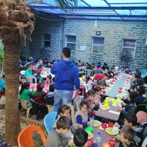 dzieci siedzą przy stole i jedzą posiłek