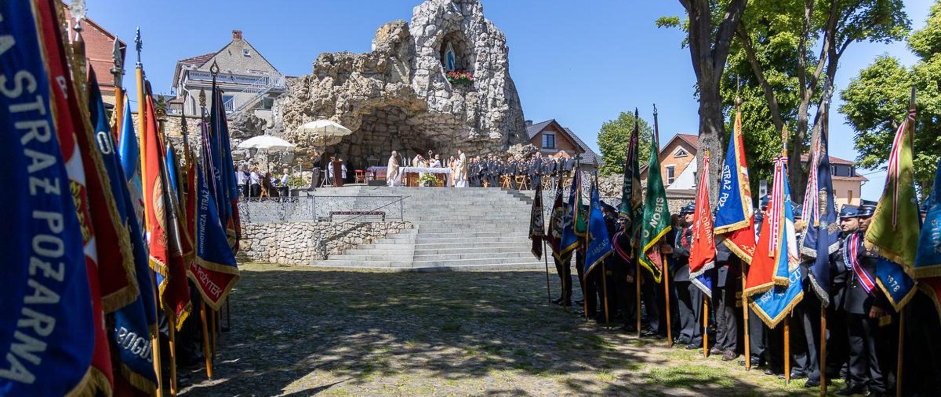 Poczty sztandarowe OSP i PSP ustawione przy grocie na Górze Świętej Anny. Rozpoczęcie Mszy Świętej w ramach pielgrzymki strażaków na Górę Świętej Anny.