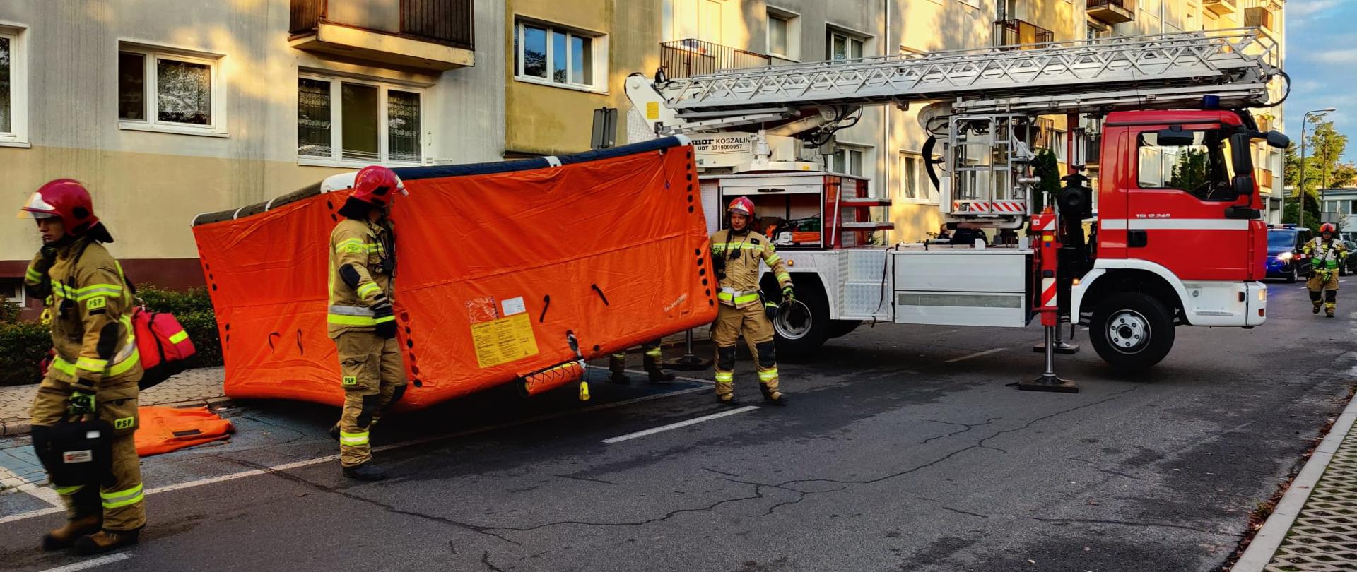 na miejscu ratownicy rozkładają skokochron za nimi rozstawiany jest podnośnik hydrauliczny SH-24