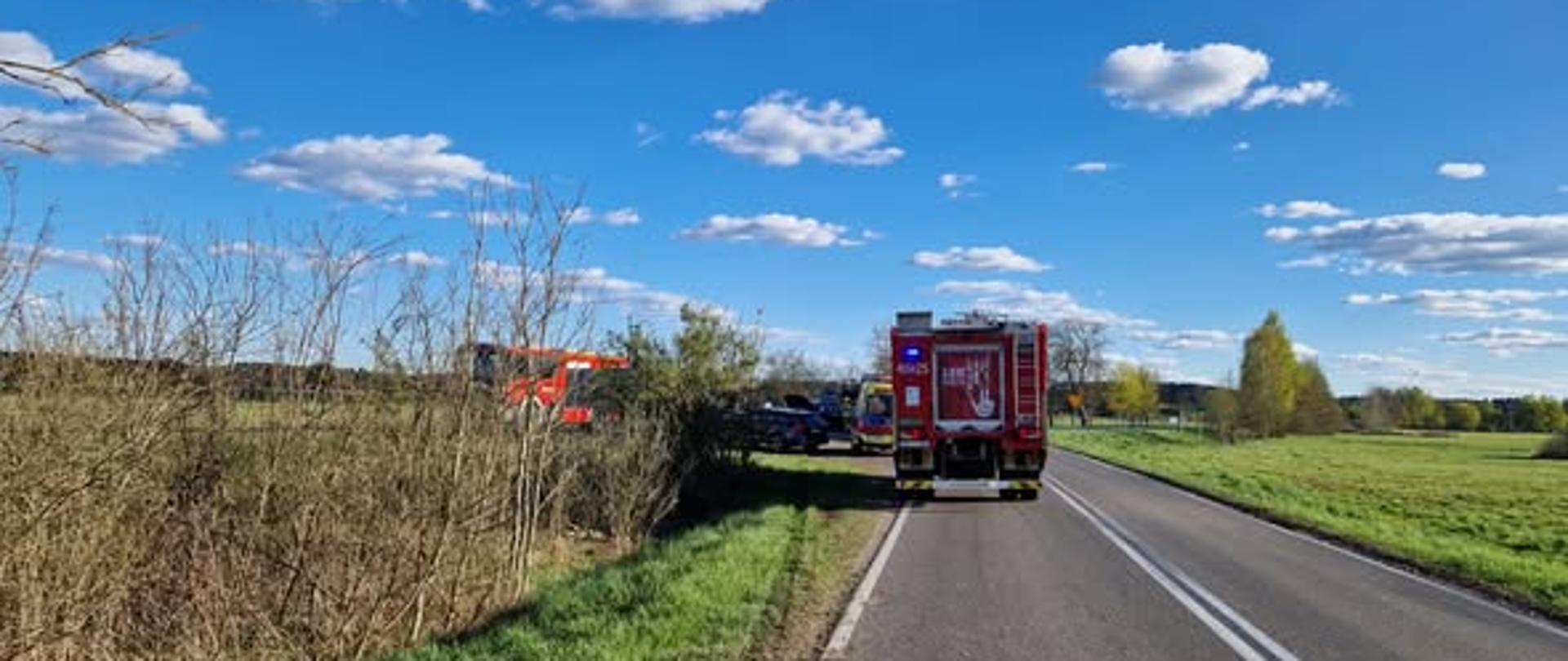 Samochód rozbity na drodze. W tle wóz strażacki