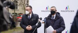 Wiceminister rozwoju, pracy i technologii Robert Tomanek, po jego lewej stronie stoi wicemarszałek Małopolski Tomasz Urynowicz. Politycy stoją przy mikrofonach, za ich plecami baner z napisami "Małopolska".