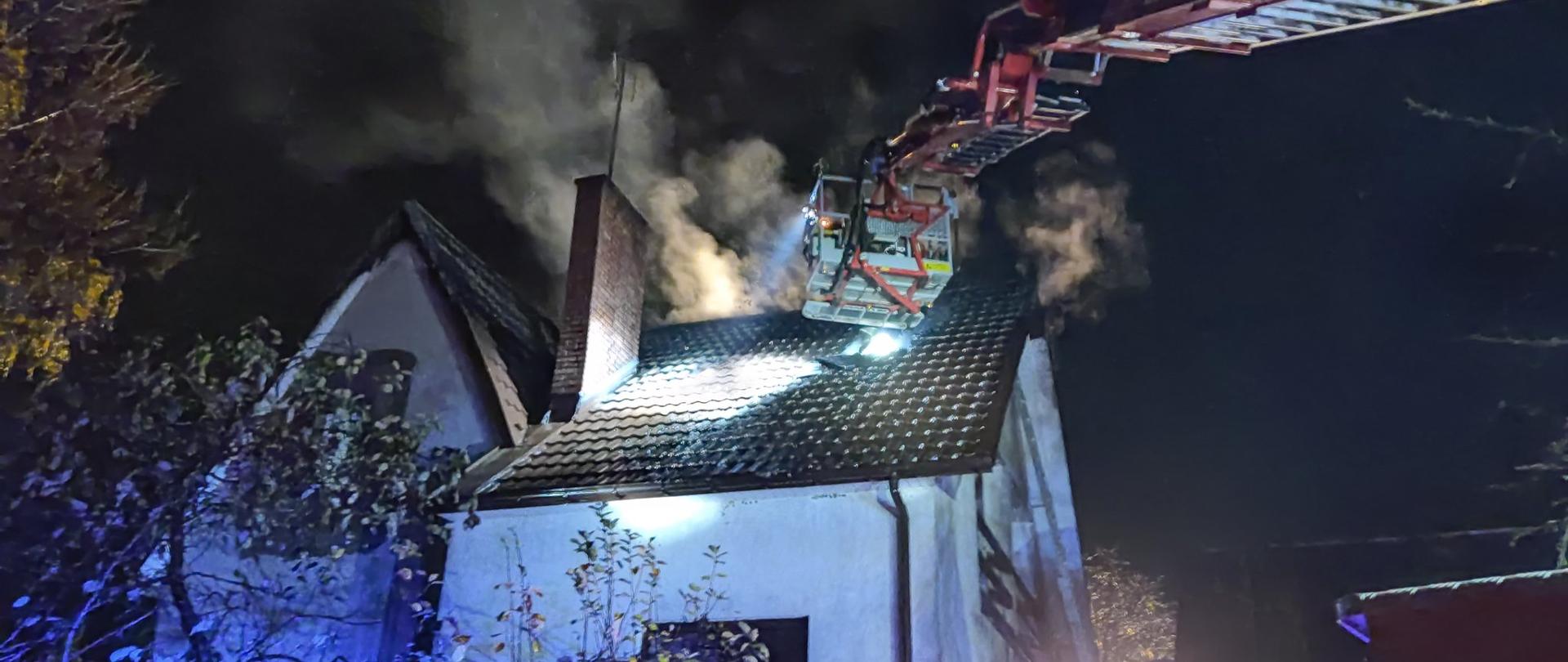 Zdjęcie przedstawia akcję gaśniczą budynku mieszkalnego z podnośnika hydraulicznego