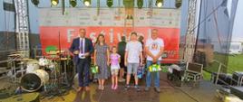 Kobieta i trzech mężczyzn stoi na scenie na tle banera „Festiwal Wsi Polskiej 
