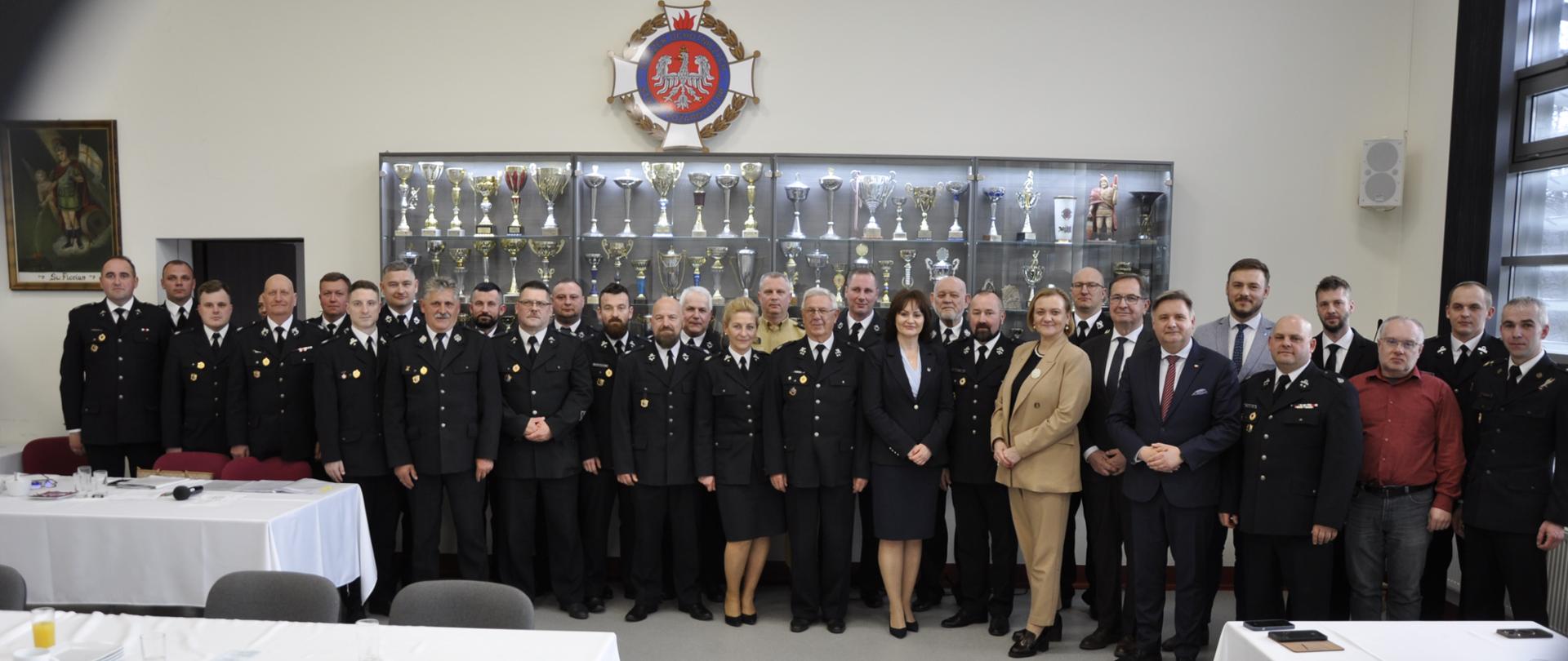 Zdjęcie grupowe po zakończonym zebraniu gminy Żukowo. W tle gablota z pucharami.