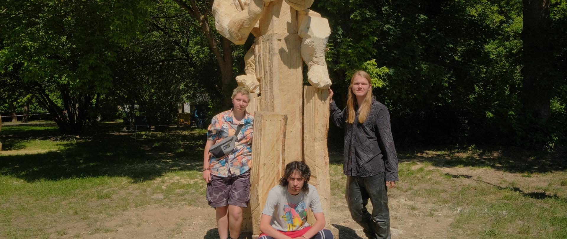 Teren Leśnego Parku Kultury w Bydgoszczy, uczestnicy pleneru rzeźbiarskiego i stworzona praca.
