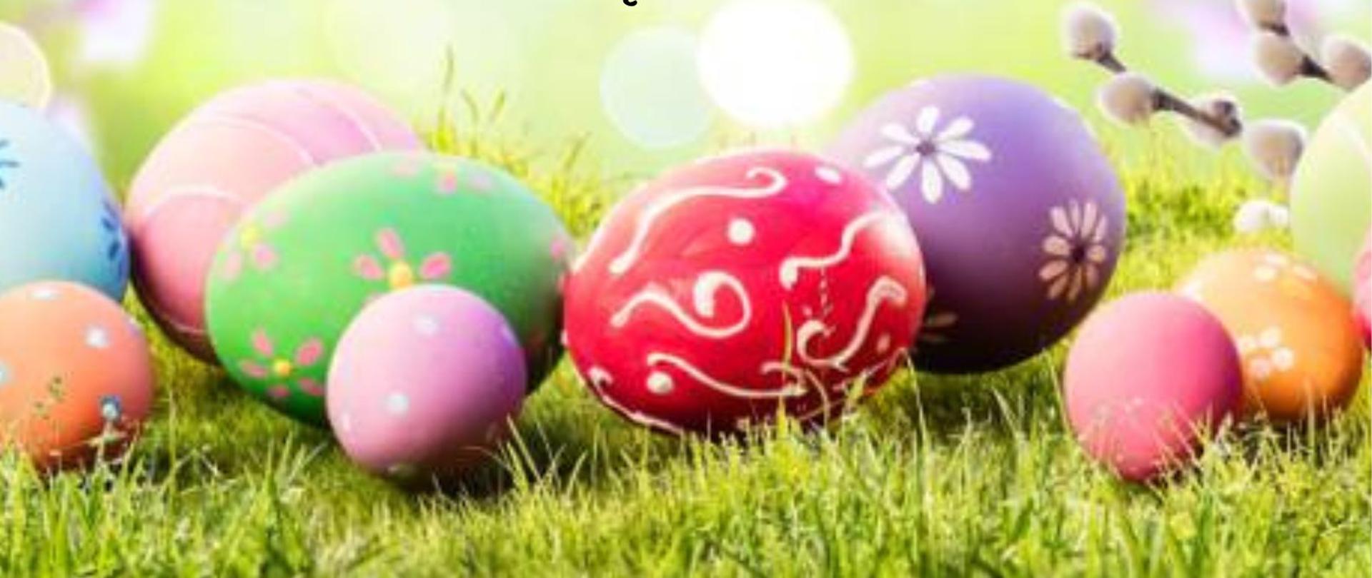 Niebieskie tło, na dole kolorowe pisanki na trawie, życzenia wielkanocne od pracowników i uczniów ZSM w Częstochowie