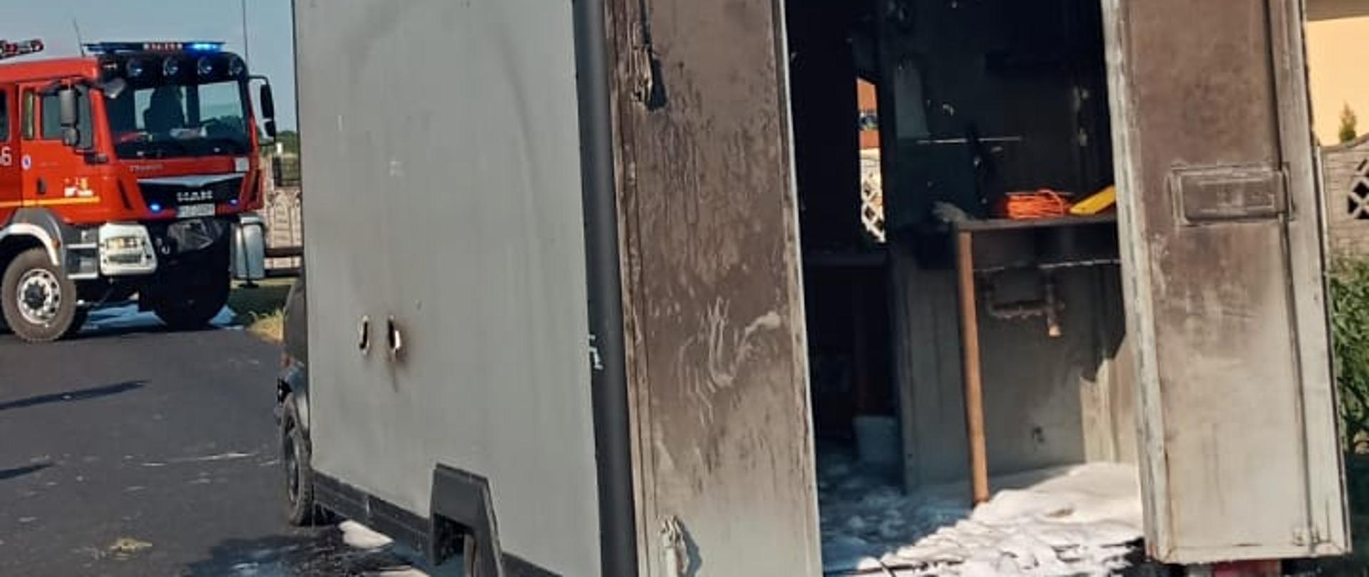 Tył spalonej furgonetki zalane pianą gaśniczą. W tle widać samochód ratowniczo-gaśniczy.