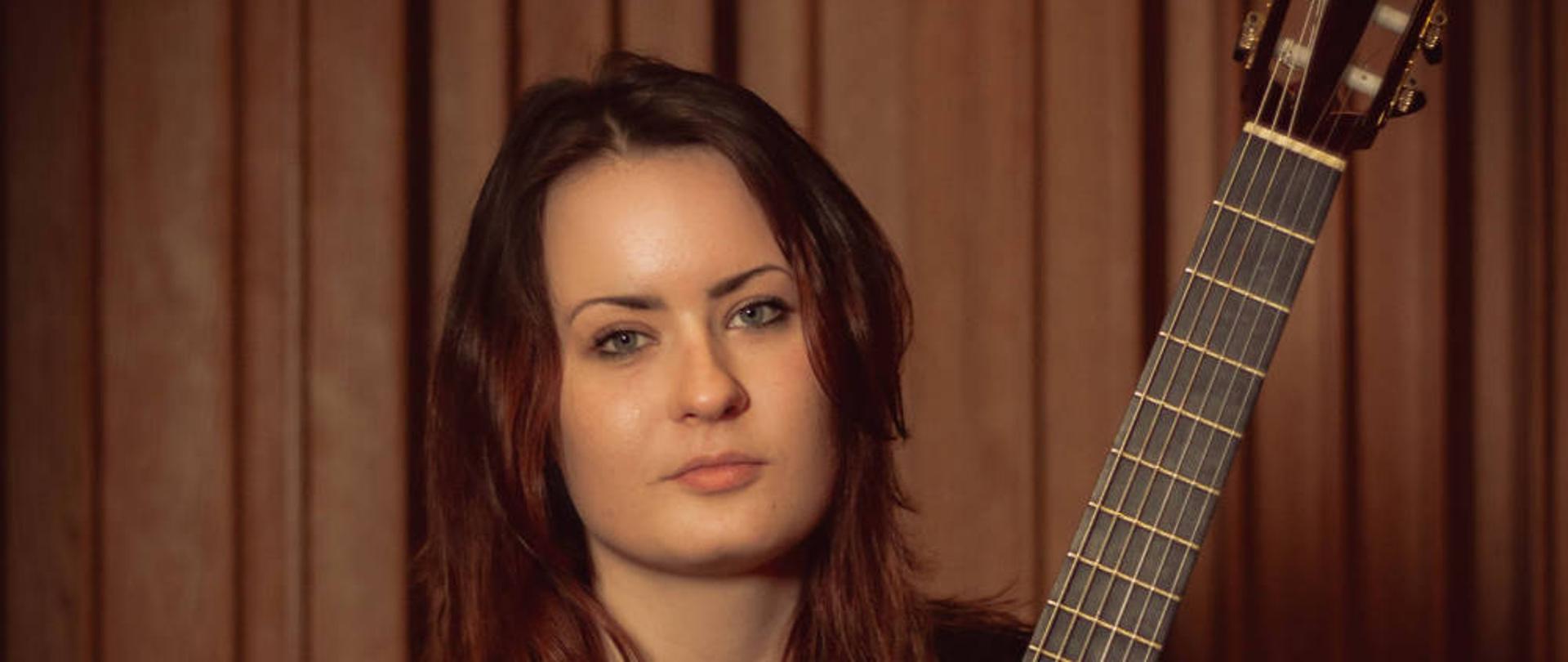 Plakat recitalu dyplomowego Zuzanny Bonarskiej. Przedstawia zdjęcie wykonawczyni recitalu z gitarą. Na ciemnym tle. Na plakacie białą czcionką napisany jest program recitalu, data, oraz nazwiska wykonawczyni oraz nauczyciela.