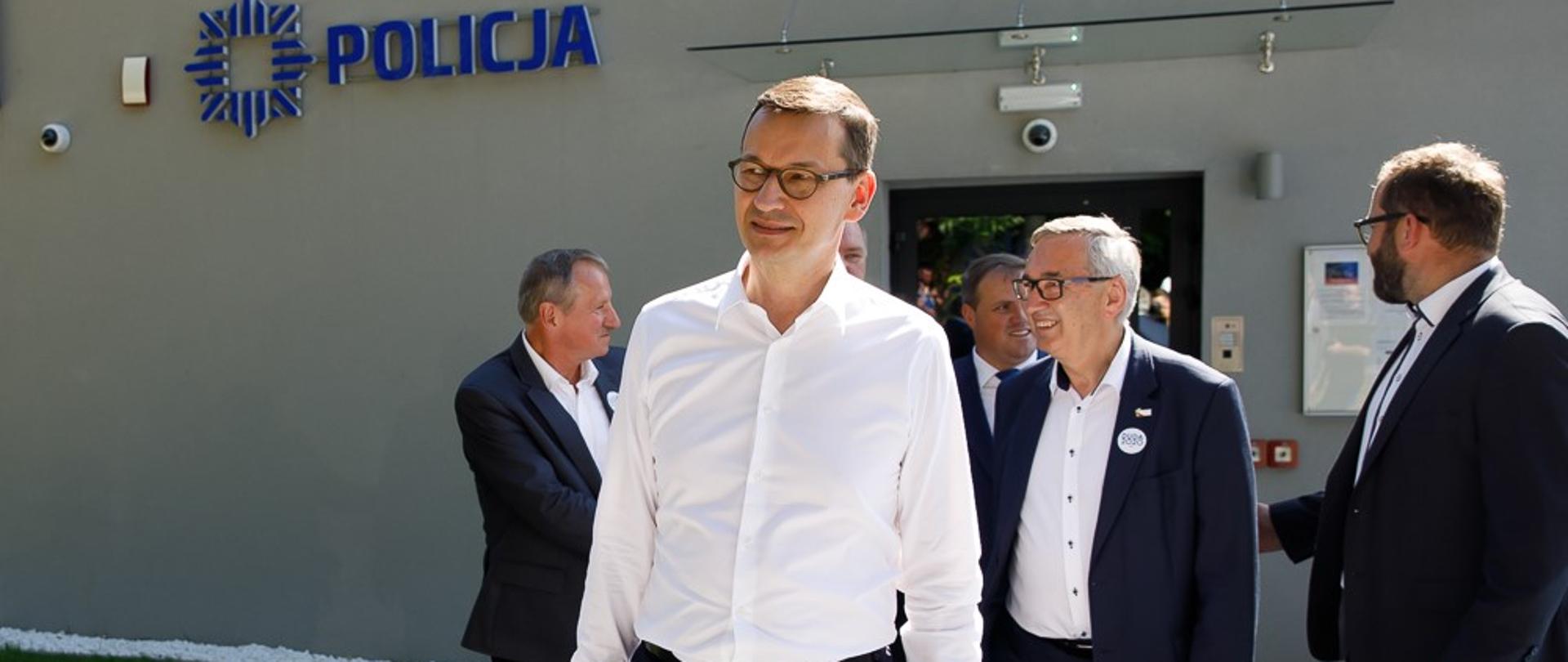 Premier wychodzi z budynku policji.