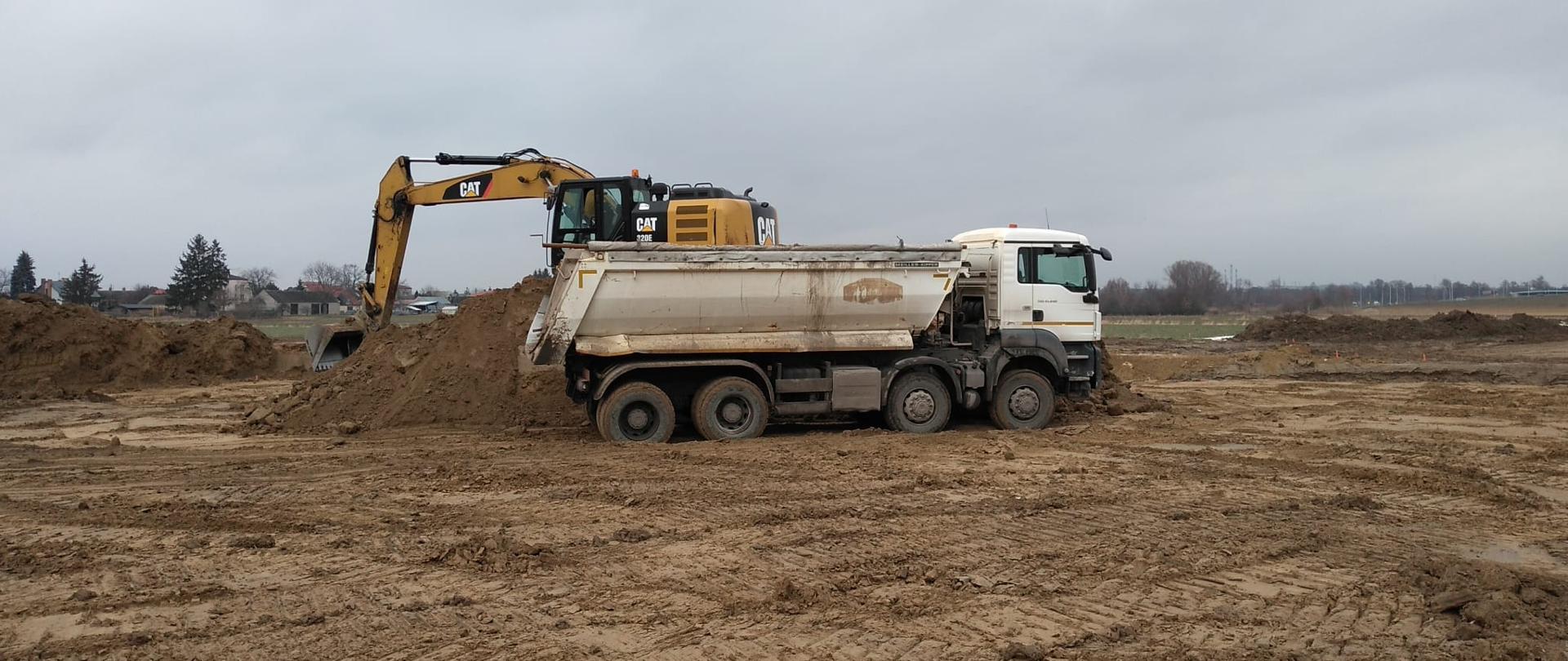DK9 obwodnica Ostrowca Świętokrzyskiego - roboty ziemne, koparka ładuje ziemię z hałd na wywrotkę 
