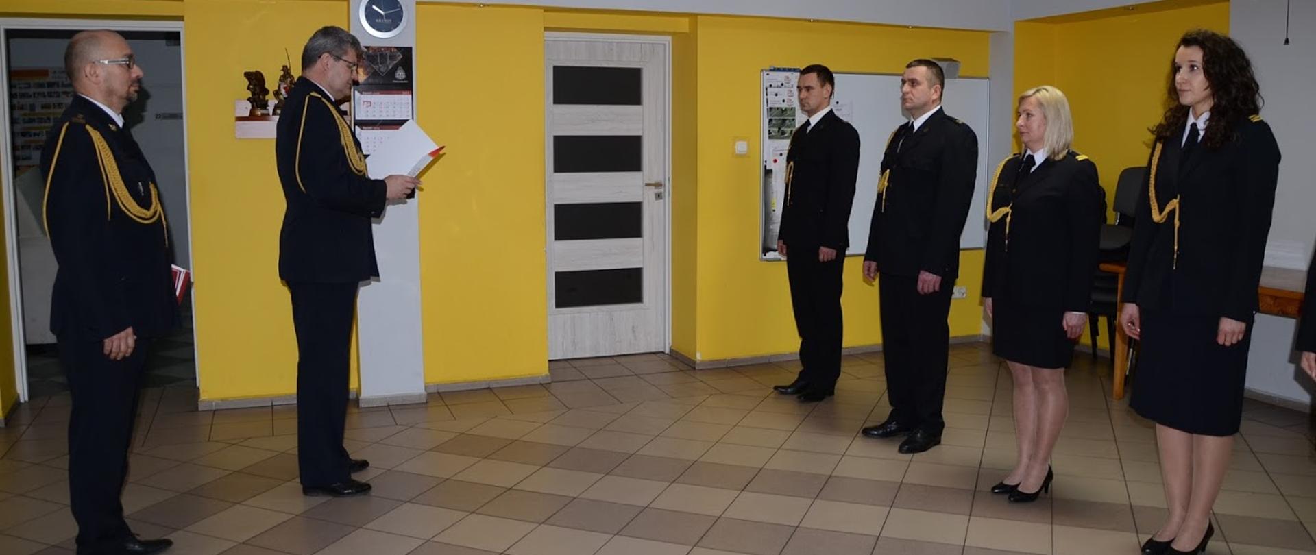 Zdjęcie przedstawia Komendanta Powiatowego czytającego akt mianowani oraz innych funkcjonariuszy.