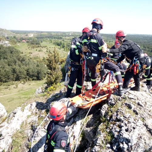 Na szczycie góry grupa ratowników ćwiczy ewakuację poszkodowanego na noszach