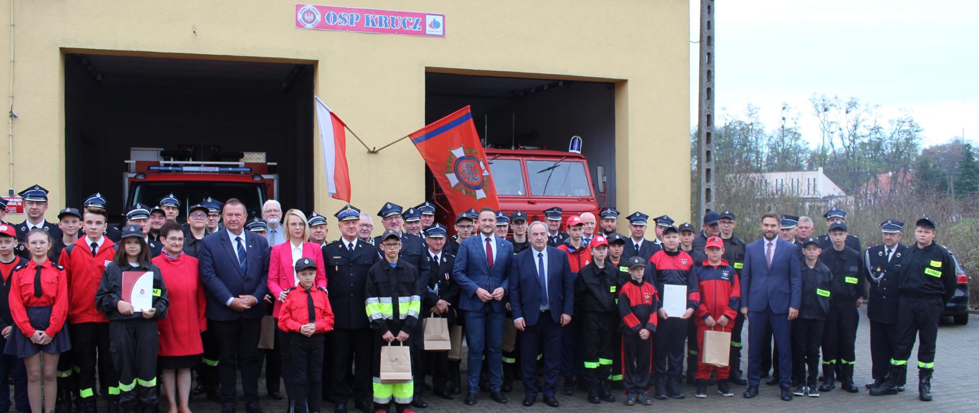 Wspólne zdjęcie uczestników uroczystości przed strażnicą OSP KSRG w Kruczu.