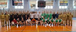 Strażacy stoją na sali sportowej podczas turnieju w piłce siatkowej