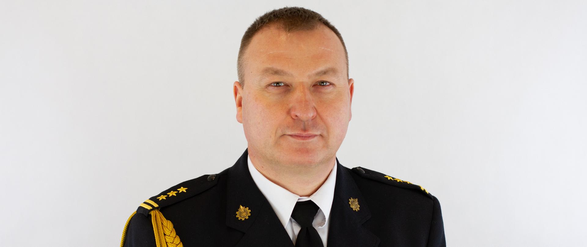 Zdjęcie przedstawia mężczyznę w wieku około 45 lat, ubranego w mundur wyjściowy z odznaczeniami, złotym sznurem.