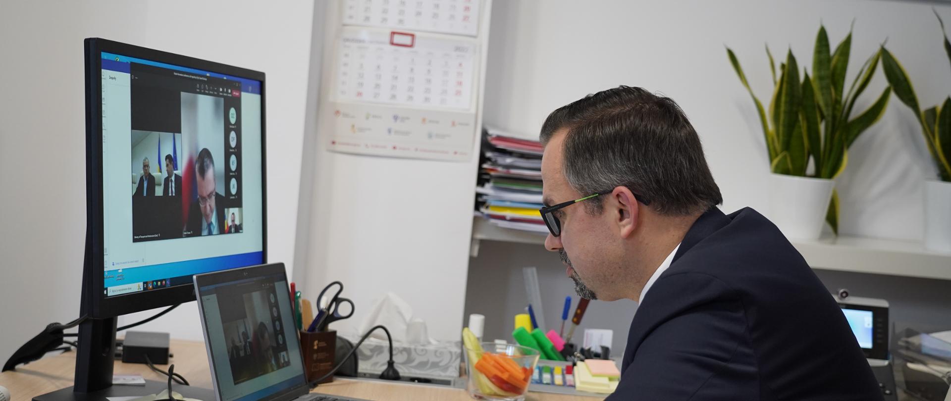 Wiceminister Marcin Horała siedzi na fotelu przed ekranem komputera.