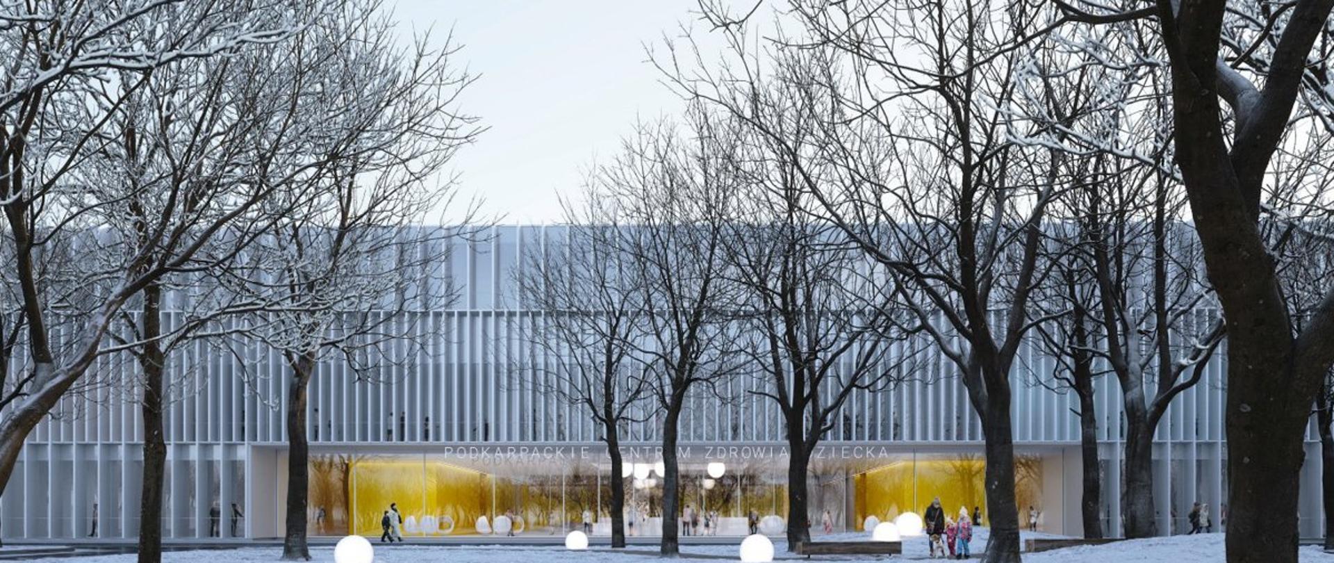 Wizualizacja Podkarpackiego Centrum Zdrowia Dziecka - przedstawia biały budynek w kształcie prostokąta z oświetlonym wejściem, nad którym znajduje się napis Podkarpackie Centrum Zdrowia Dziecka, przed budynkiem ośnieżone drzewa i przechodnie. 