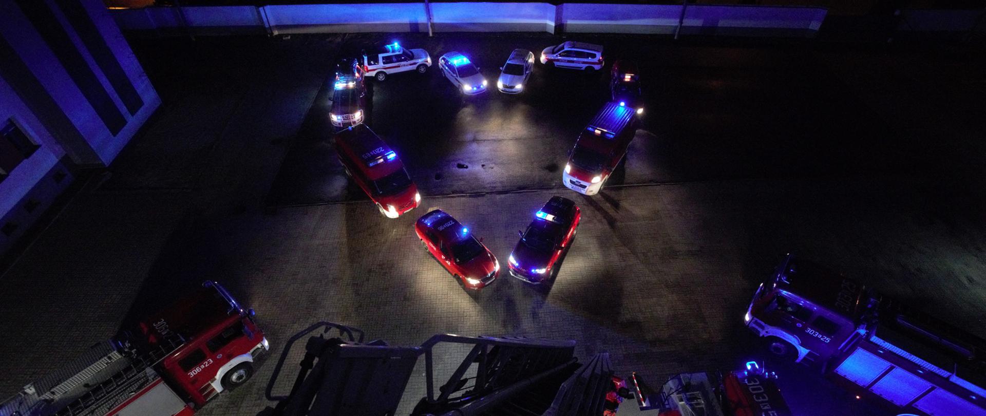 Samochody pożarnicze ustawione w kształt serca z włączonymi światłami alarmowymi 