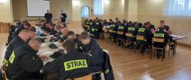 Zdjęcie przedstawia druhów OSP na sali szkoleniowej podczas egzaminu szkolenia podstawowego. 