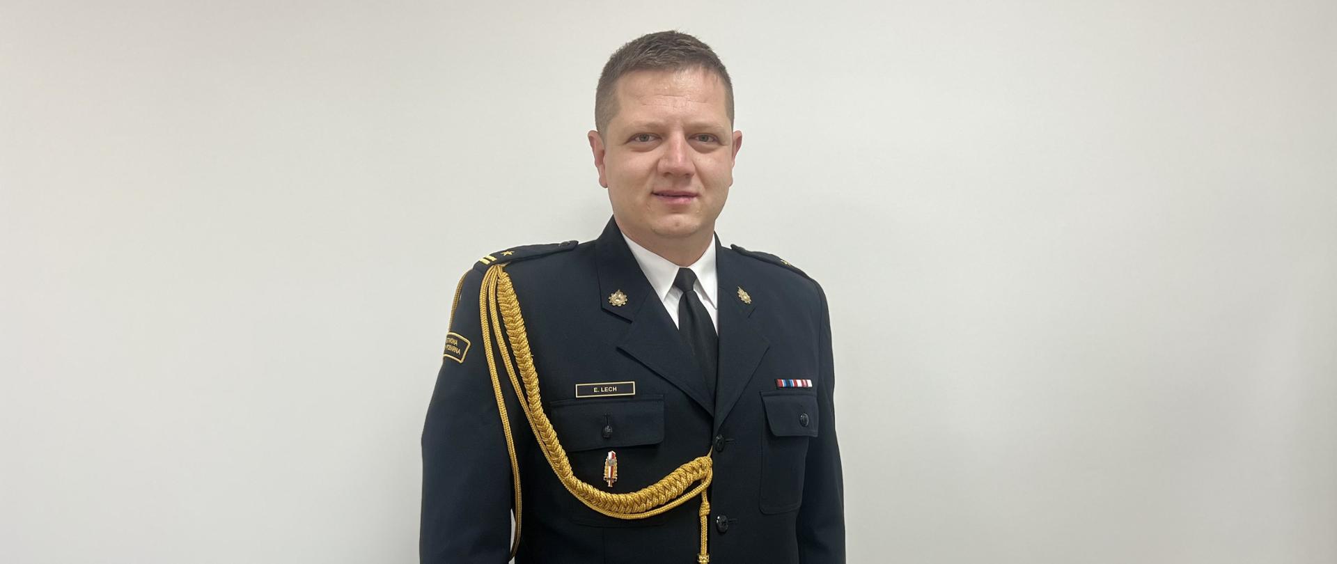 Zdjęcie przedstawia zastępcę komendanta powiatowego PSP w Tomaszowie Mazowieckim ubranego w mundur galowy ze złotym sznurem. 