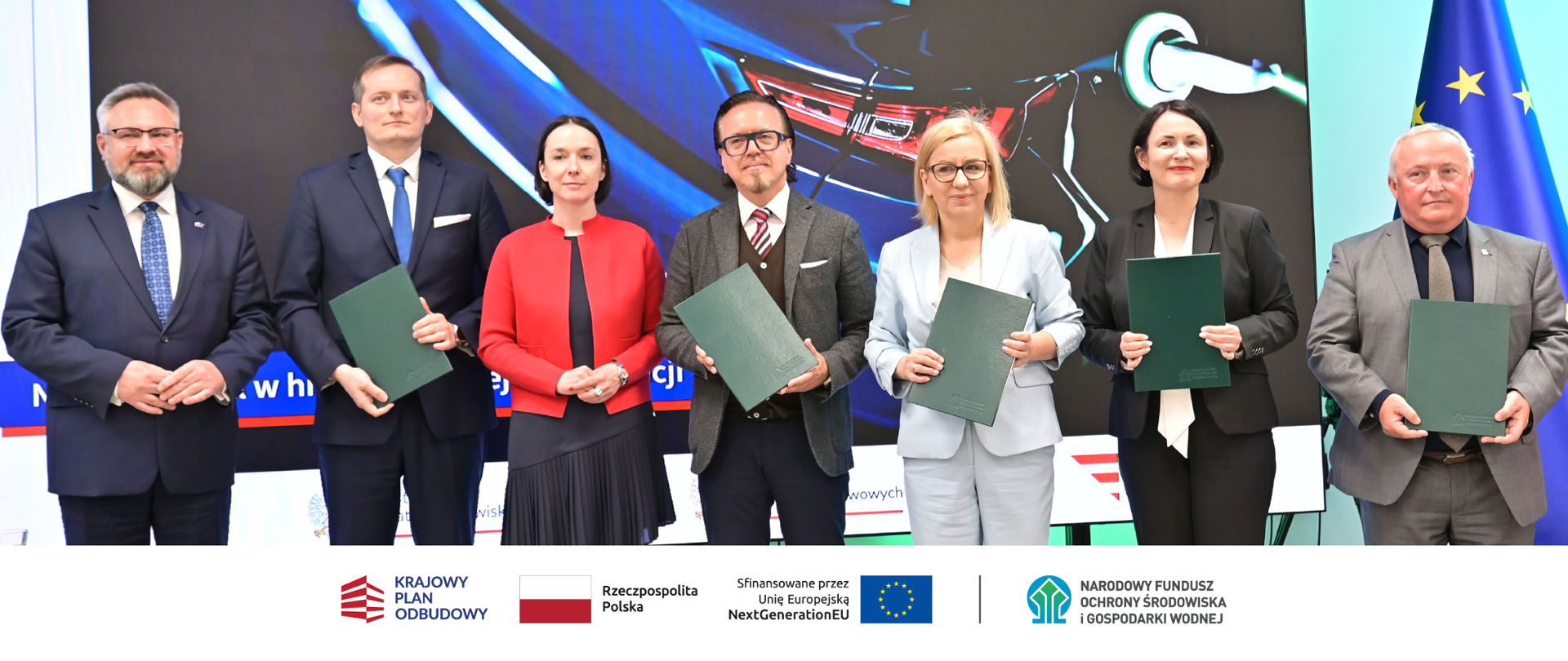 Zdjęcie grupowe. Na dole zdjęcia ciąg logotypów: W stopce grafiki ciąg logotypów: Krajowy Plan Odbudowy, flaga Rzeczypospolita Polska, flaga UE Sfinansowane przez UE NextGenerationUE, NFOŚiGW.