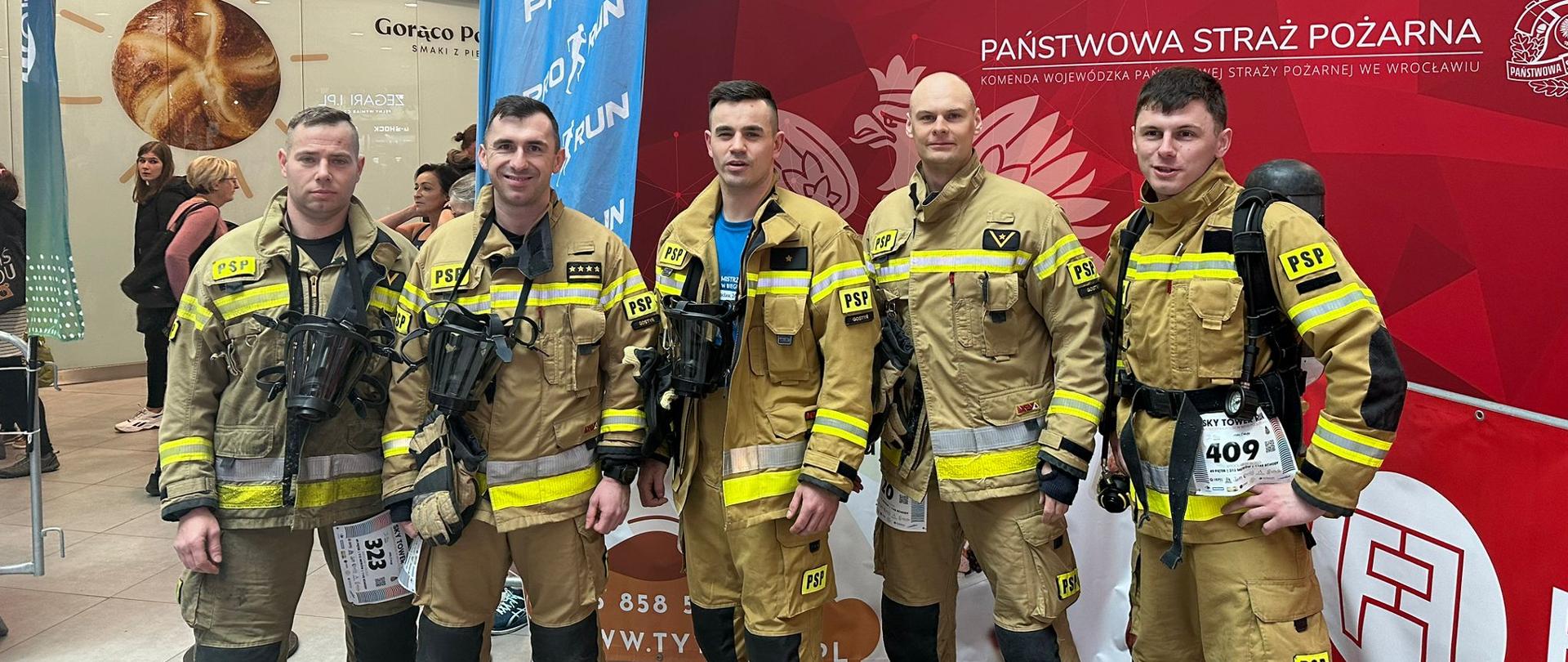 Strażacy stoją przed startem w zawodach.