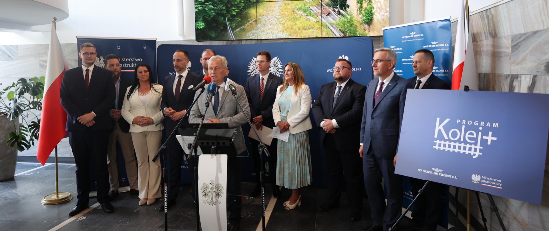 Hol OUW. 11 uczestników briefing na ściance z logo Wojewody