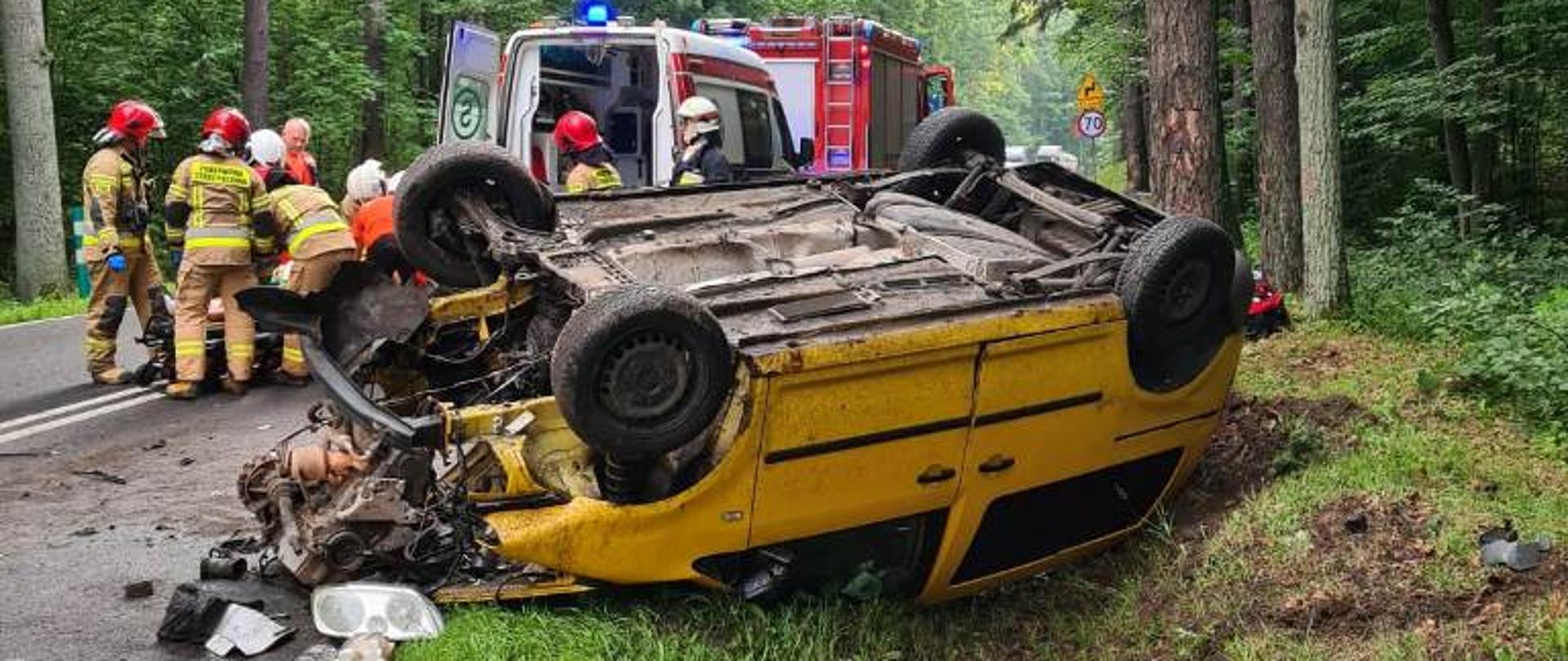 Strażacy i ratownicy medyczni przygotowują poszkodowanego do tran sportu do szpitala