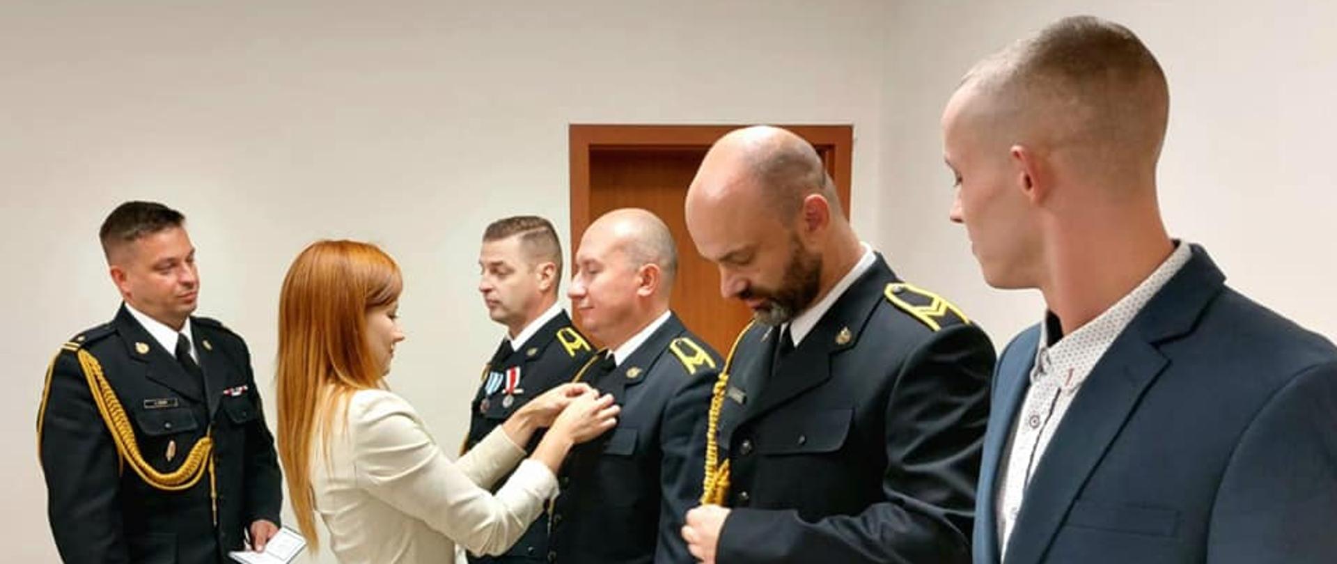 Zdjęcie przedstawia zaszczytne wyróżnienie otrzymało trzech funkcjonariuszy PSP ze Słupska : st. ogn. Tomasz Kotusiewicz, st. ogn. Hubert Kuliński i st. ogn. Grzegorz Załupka. Odznaczenia wręczała z up. Derektora RCKiK w Słupsku Pani Magdalena Żynis kierownik sekcji w RCKiK w asyście komendanta miejskiego PSP w Słupsku mł. bryg. Krzysztofa Trockiego.