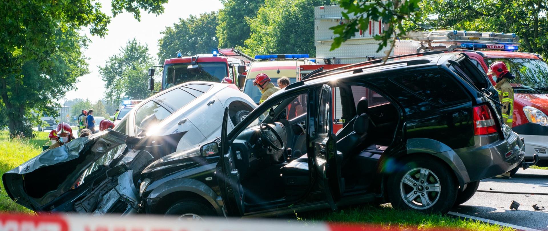 Na zdjęciu pojazdy osobowe w rowie na jezdni samochody pożarnicze teren ogrodzony taśmą ostrzegawczą